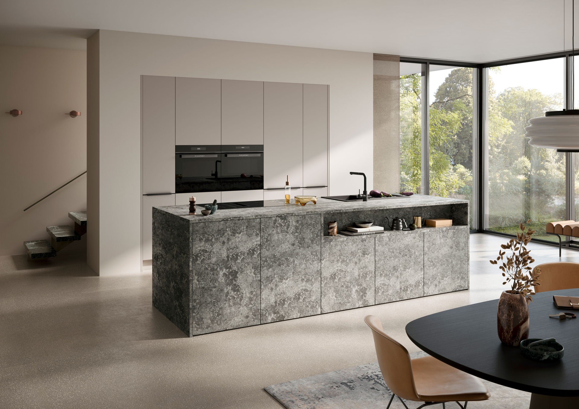 Hochschrankwand in Steinbeige mit zwei Backöfen und dunkler Griffleiste hinter der Kücheninsel in Anthrazit, Häcker concept130