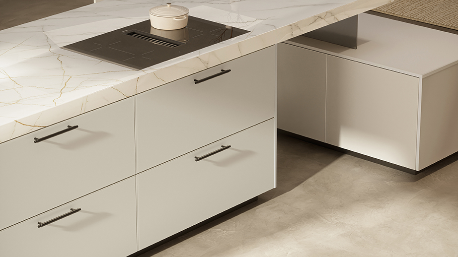 Kitchen island in a beige kitchen with a cooktop featuring an integrated range hood by Häcker